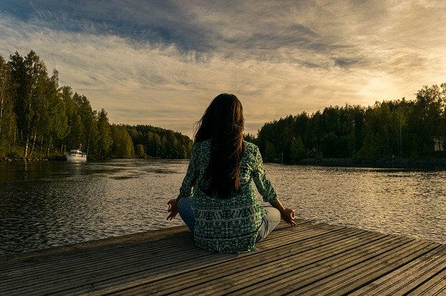 Woman meditating peacefully by a lake